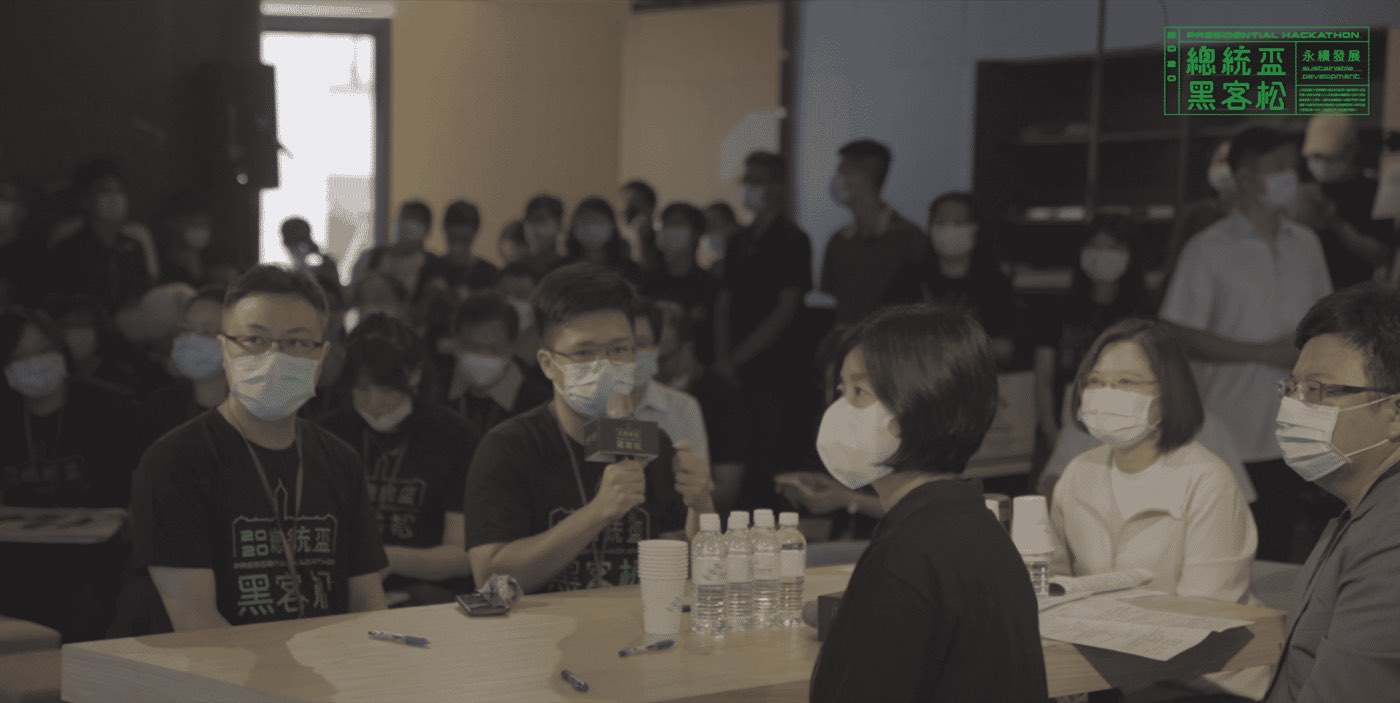 Aaron Gao, holding the event microphone, presents team WayFic at the 2020 Taiwan Presidential Hackathon finals; President Tsai Ing-wen sits in the audience.